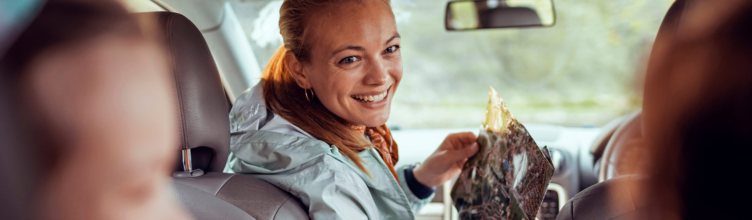 Women smiling in car looking at kids in back seat